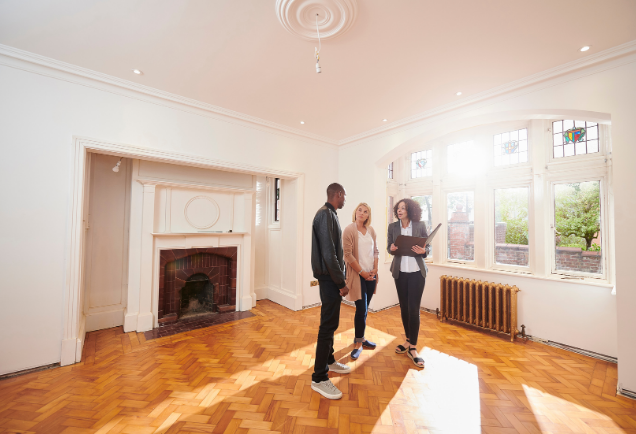 Real estate agent showing an empty house to a couple, property management.